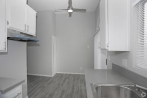 a kitchen with white cabinets and a ceiling fan  at The Marq Apartments LLC, Los Angeles, California