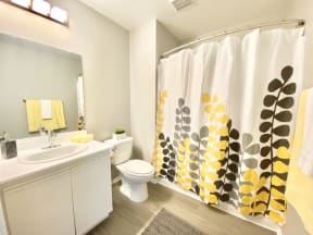 a bathroom with a shower curtain and a sink and a toilet at BLVD Apartments LLC, Tarzana, CA 91356
