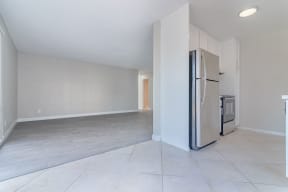 an empty kitchen and living room with a refrigerator at Citra Apartments LLC, San Diego