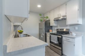 Kitchen with stainless steel appliances and white cabinets at The Gates at the Marina Apartments, California, 93933