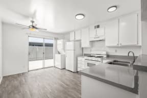 a kitchen with white cabinets and white appliances and a sliding glass door at Ocean Villas, Oxnard, CA 93033