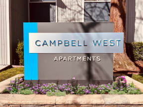 a sign that says apartments in front of flowers at Campbell West Apartments, California