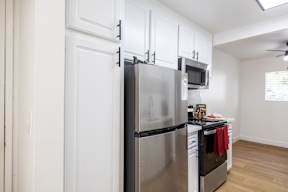 A kitchen with a stainless steel refrigerator and black countertops.