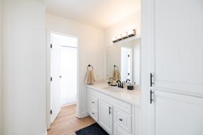 A bathroom with a white vanity and a mirror above it.