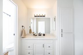A white bathroom with a mirror and a towel hanging on the wall.