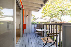A balcony with a table and chairs overlooking a backyard.