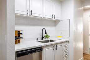 A kitchen with white cabinets and a black dishwasher.