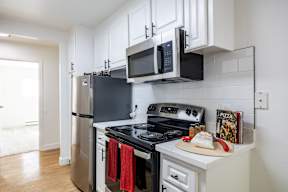 A kitchen with black appliances and white cabinets.