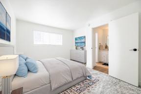 A bedroom with a bed, nightstand, and a painting on the wall.