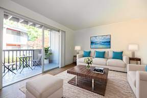 A living room with a white couch, a coffee table, and a painting on the wall.