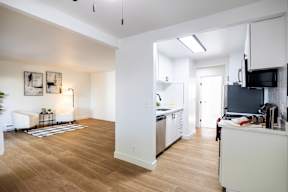 A kitchen with white cabinets and a wooden floor.