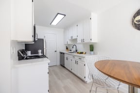 a white kitchen with white cabinets and a wooden table and counter top at Campbell West Apartments, Campbell, CA