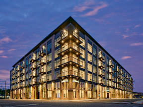 A modern building with a lot of windows and lights on.