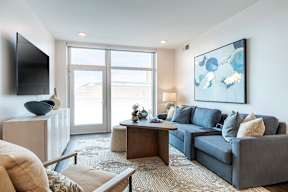 A living room with a grey couch, a coffee table, and a painting on the wall.