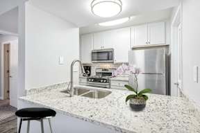 A kitchen with a granite countertop and a black stool.