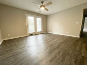 an empty living room with wood floors and a ceiling fan