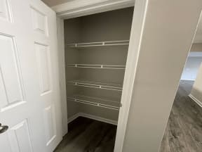 a walk in closet with empty shelves and a door