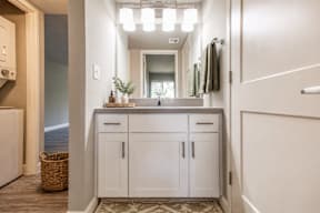 A bathroom with a white cabinet and a mirror above the sink.