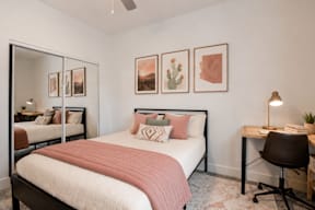 A bedroom with a bed, desk, chair, and pictures on the wall.