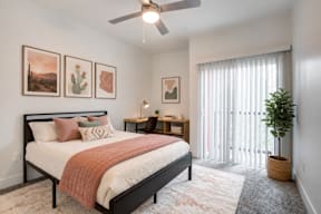 A bedroom with a bed, a ceiling fan, and a plant.