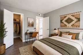 A bedroom with a large bed and a woven wall hanging.