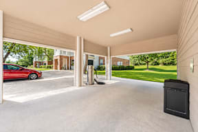 A red car is parked in a garage with a black box on the floor.