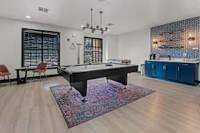 A pool table is in the middle of a room with a rug on the floor.