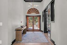 A hallway with a wooden bench and a rug on the floor.