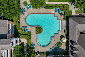 An aerial view of a swimming pool surrounded by trees and houses.