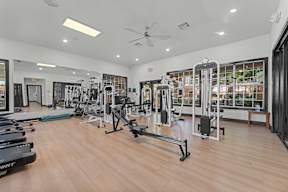 A gym with a variety of equipment including treadmills, weights, and a bench.