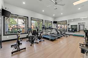 A spacious gym with a variety of exercise equipment and a television.