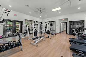 A gym with a variety of equipment including treadmills, weights, and exercise machines.