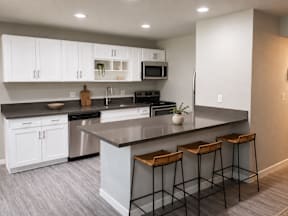 A kitchen with white cabinets and a black countertop.