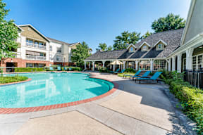 A swimming pool surrounded by a building and a gazebo.