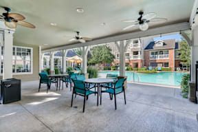 A patio with a table and chairs and a ceiling fan.