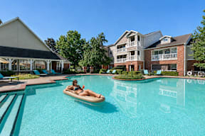 A woman is sunbathing in a pool at a resort.