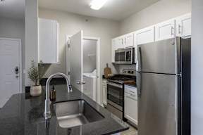 A kitchen with a black counter top and stainless steel appliances.