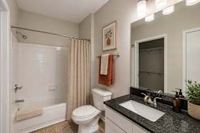 A bathroom with a white toilet, a white sink, a white bathtub, and a shower curtain.