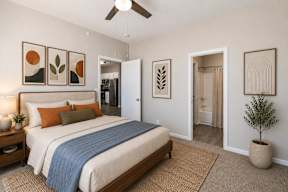 A bedroom with a bed, a ceiling fan, and a plant.