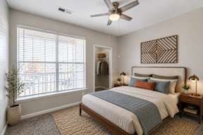 A bedroom with a bed, a ceiling fan, and a window with blinds.