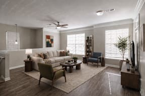 A living room with a white ceiling fan and a grey couch.