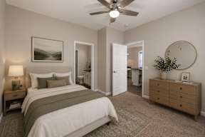 A bedroom with a bed, nightstand, and a painting on the wall.