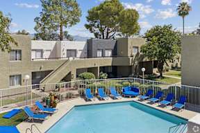 A swimming pool surrounded by blue chairs and apartment buildings.