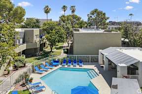 A pool surrounded by trees and chairs.