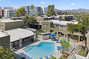 A pool surrounded by a fence and chairs in a courtyard.