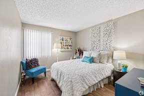 A bedroom with a large bed and a blue chair.