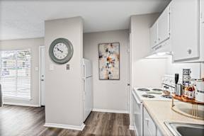 A kitchen with a white fridge and a clock on the wall.