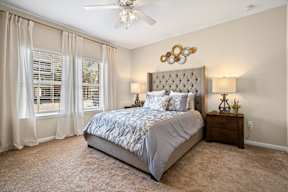 A bedroom with a large bed and a ceiling fan.