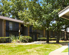 A row of apartment buildings with green trees in front.