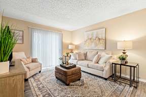 A living room with a couch, a coffee table, and a potted plant.